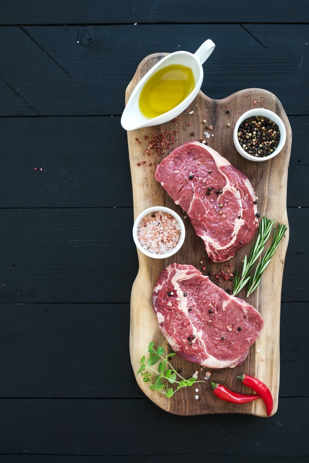 raw-fresh-meat-ribeye-steak-entrecote-and-seasonings-on-cutting-board-over-dark-wooden-background-.jpg