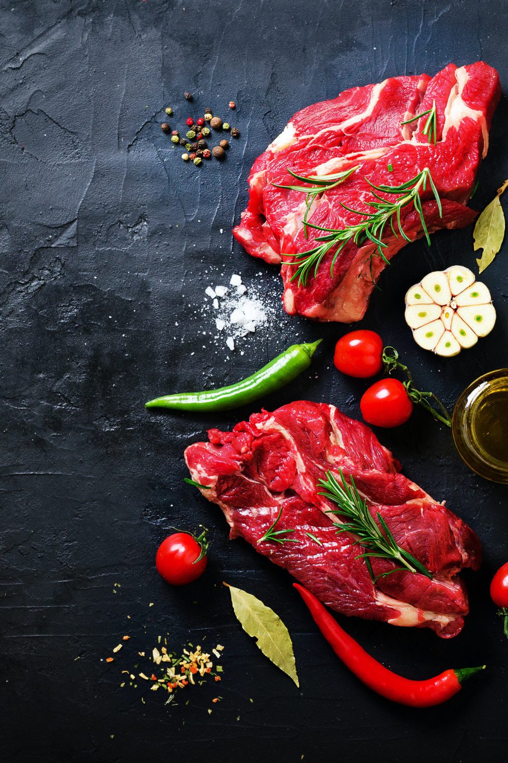 raw-meat-beef-steak-on-a-stone-cutting-board-with-rosemary-spices-salt-oil-cherry-tomatoes-hot.jpg
